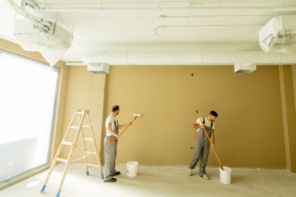 two men painting a wall in yellow